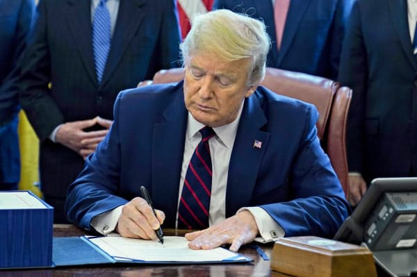 経済対策法案に署名するトランプ米大統領(27日、ワシントン)=AP