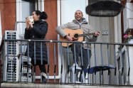 バルコニーでギターを演奏する男性(ミラノ)=ロイター バルコニーでギターを演奏する男性(ミラノ)=ロイター