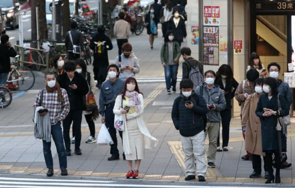 マスクを付けて信号を待つ人たち(4日、東京都新宿区)