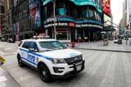 人通りが途絶えたタイムズクエアを警備するNY市警の車両=ロイター 人通りが途絶えたタイムズクエアを警備するNY市警の車両=ロイター