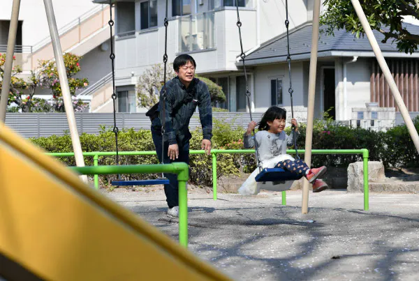 子どものブランコを押す練馬区に住む会社員の男性(40)。新型コロナウイルスの影響で保育園が休みになり、子どもたちの体調管理のためにも1日1回は外に出るというが、なるべく人と接触しないよう心掛けているという(8日午前、東京都練馬区)=藤井凱撮影