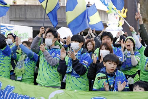 2月にJリーグが開幕し、選手を迎える湘南のサポーター。新型コロナウイルス感染予防のため、マスク姿の観客が目立った=共同