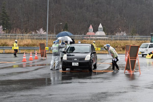 専用レーンに誘導し、検温に協力を求める県職員(18日、山形市の山形蔵王パーキングエリア)