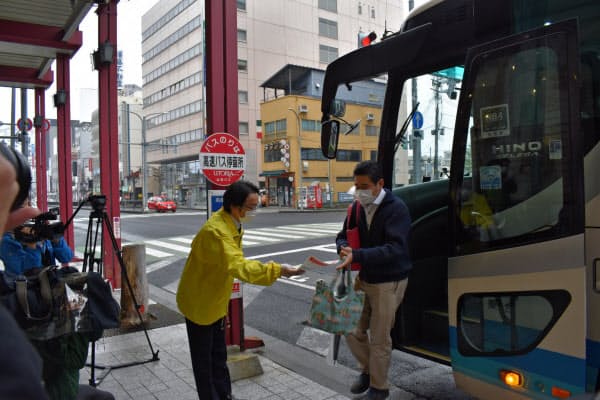 仙台~山形間の高速バスを降りる乗客にチラシを配る県職員(18日、山形市)