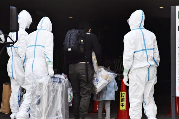 入院中の医療機関から療養先となるホテルに到着した人たち(中央)(15日午後、さいたま市)=共同