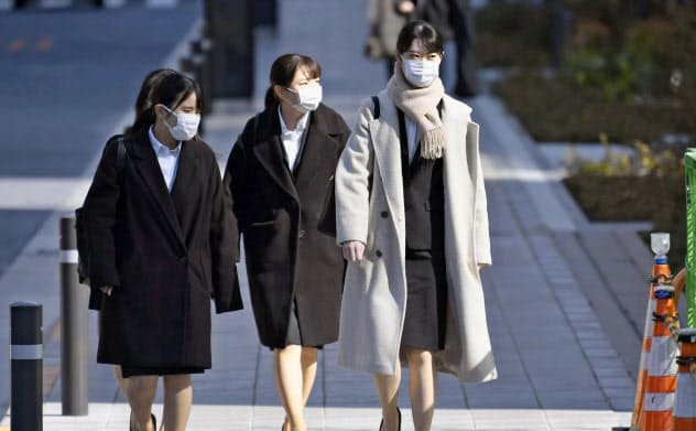 マスク姿で合同会社説明会の会場に向かう就職活動の学生ら(3月、東京都港区)=共同 マスク姿で合同会社説明会の会場に向かう就職活動の学生ら(3月、東京都港区)=共同