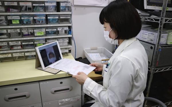 薬剤師がテレビ電話で患者とやりとりする（東京都港区の「ナチュラルローソンクオール薬局城山トラストタワー店」）=一部画像処理しています
