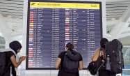 バリ島で国際線の運航状況をチェックする外国人旅行客(3月)=AP バリ島で国際線の運航状況をチェックする外国人旅行客(3月)=AP