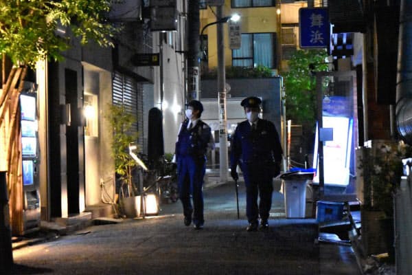 人けのない飲み屋街をパトロールする警察官(28日夜、東京都港区)