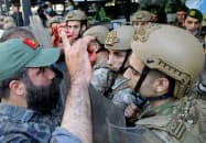 治安部隊と対峙するデモ参加者の男性(左)(1日、ベイルート)=ロイター 治安部隊と対峙するデモ参加者の男性(左)(1日、ベイルート)=ロイター