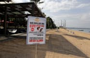マスク着用を促す看板が立てられたインドネシアのバリ島のビーチ(4月14日)=AP マスク着用を促す看板が立てられたインドネシアのバリ島のビーチ(4月14日)=AP
