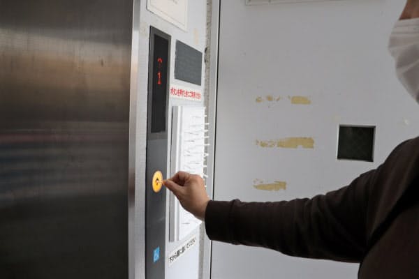 JR湯河原駅近くのエレベーターのボタンを綿棒で押す住民(4月、神奈川県湯河原町)