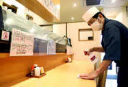 開店前にテーブルを消毒する居酒屋の店主(14日、名古屋市東区) 開店前にテーブルを消毒する居酒屋の店主(14日、名古屋市東区)