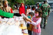 新型コロナウイルスの感染拡大が続くインドネシアで食料の配給を受ける子供ら(5月14日、ジャカルタ)=ロイター 新型コロナウイルスの感染拡大が続くインドネシアで食料の配給を受ける子供ら(5月14日、ジャカルタ)=ロイター