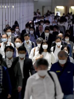 マスク姿で通勤する人たち(18日午前、東京都新宿区)