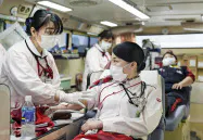 献血する日本航空の大友あゆみさん(右、20日午後、羽田空港)=共同 献血する日本航空の大友あゆみさん(右、20日午後、羽田空港)=共同