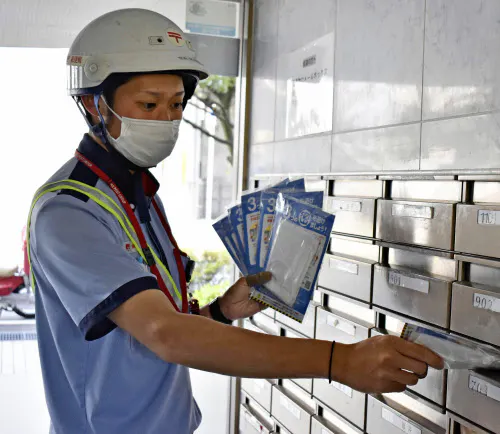 集合住宅のポストに配達されるマスク(23日午前、福井市)=共同
