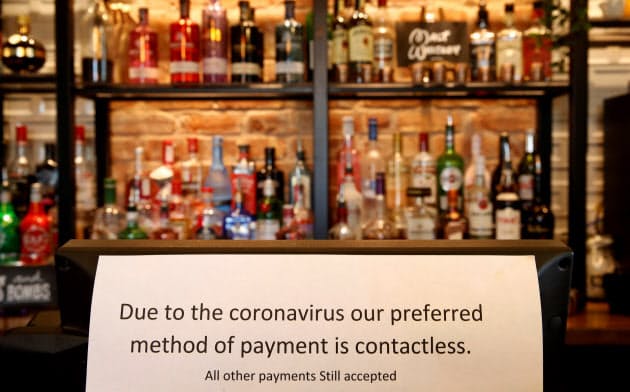 キャッシュレス決済を奨励する案内を店頭に掲げる英国のパブ。現金離れの動きは新型コロナ収束後も強まりそうだ=ロイター キャッシュレス決済を奨励する案内を店頭に掲げる英国のパブ。現金離れの動きは新型コロナ収束後も強まりそうだ=ロイター