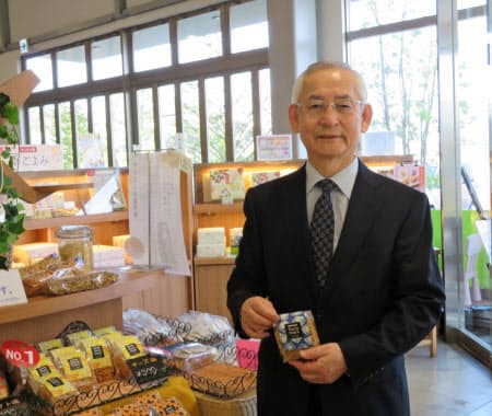 女性社員のアイデアが実を結んだパスタスナックを手にする斉之平伸一社長(同社店舗で)