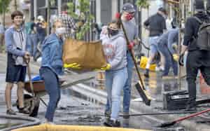 暴動で破壊された店舗の周辺を清掃するボランティア(5月29日、ミネソタ州)=AP 暴動で破壊された店舗の周辺を清掃するボランティア(5月29日、ミネソタ州)=AP