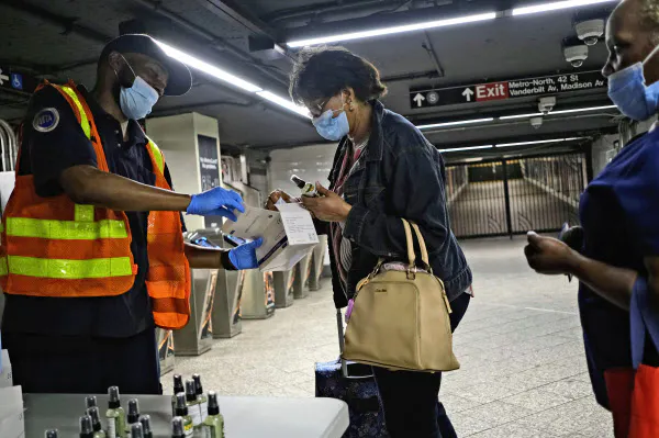 ニューヨーク市の地下鉄では職員が乗客にマスクや消毒剤を配布した(8日)=AP