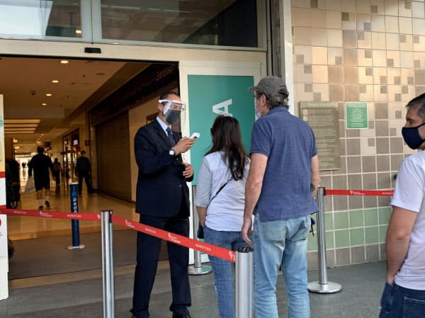 感染拡大期でも営業を再開したショッピングモールに並ぶ人々(11日、サンパウロ)