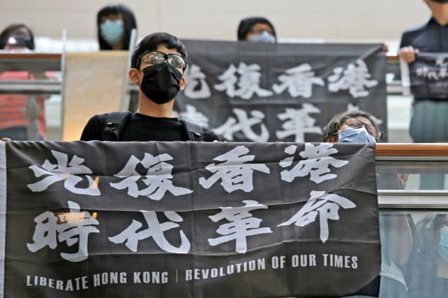 16日、香港で抗議の旗を掲げるデモ参加者=AP 16日、香港で抗議の旗を掲げるデモ参加者=AP