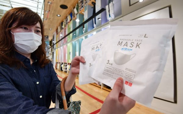 発売されたユニクロの「エアリズムマスク」を手にする女性(19日午前、東京都中央区のユニクロ銀座店)