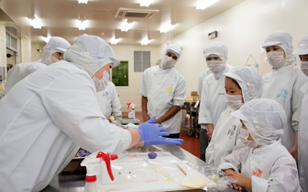 「こども参観」でお菓子づくりの説明を受ける従業員の子どもたち（2019年8月、近江八幡工場）
