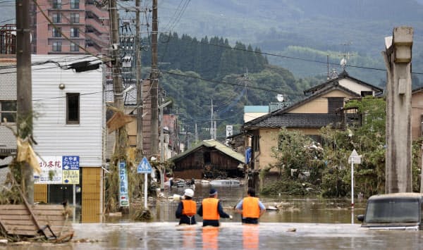 豪雨の影響で水に漬かった熊本県人吉市の市街地。取り残された人がいないか、警察官が拡声器を使い確認していた(4日午後3時49分)=共同