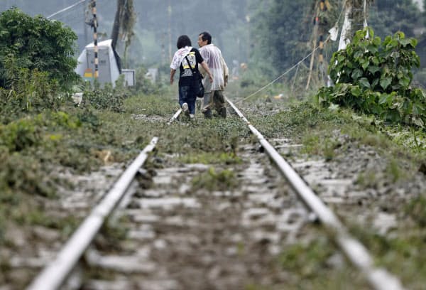 土砂が流れ込んだ熊本県球磨村の線路を歩く人たち(5日午前8時25分)=共同