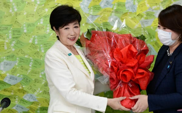 当選を決め、関係者から花束を受け取る小池百合子氏(左)=5日、東京都新宿区