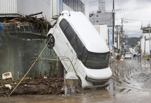熊本県人吉市の豪雨被害で、乗り上げたままの乗用車(6日午前)=共同