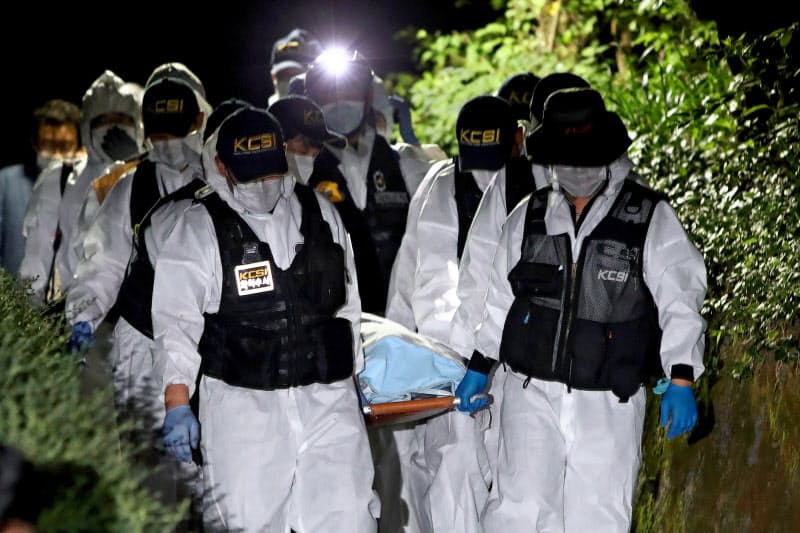 朴元淳ソウル市長とみられる遺体を運ぶ警察当局者ら(10日、ソウル)=ゲッティ・共同 朴元淳ソウル市長とみられる遺体を運ぶ警察当局者ら(10日、ソウル)=ゲッティ・共同