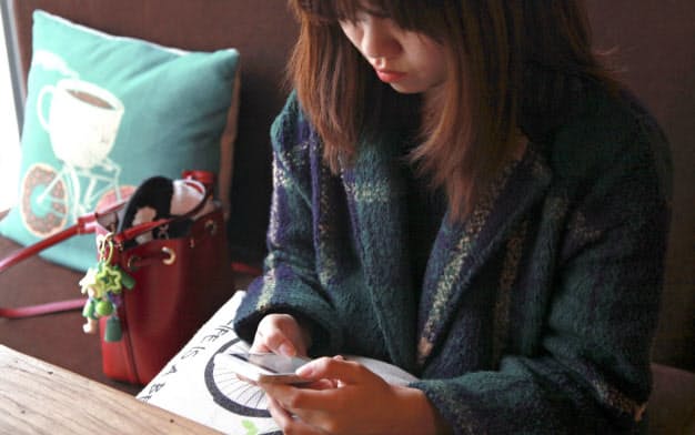 北京のカフェでスマートフォンを操作する女性=ロイター 北京のカフェでスマートフォンを操作する女性=ロイター