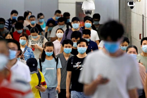 マスク姿で地下鉄駅を歩く人々(14日、北京)=ロイター