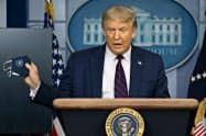 21日、トランプ米大統領は記者会見中にマスクを取り出して常に携帯していることをアピールした(ワシントン)=AP 21日、トランプ米大統領は記者会見中にマスクを取り出して常に携帯していることをアピールした(ワシントン)=AP