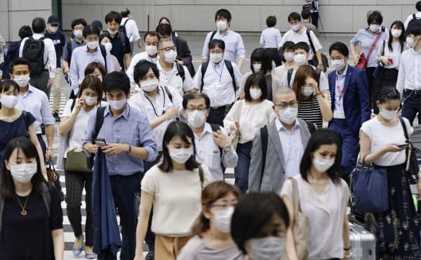東京駅前をマスク姿で歩く人たち。東京都内の新型コロナウイルスの感染者数が累計で1万人を超えた(22日午後)=共同