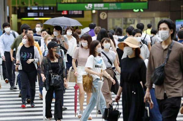 東京・新宿駅前をマスク姿で歩く人たち(25日)=共同