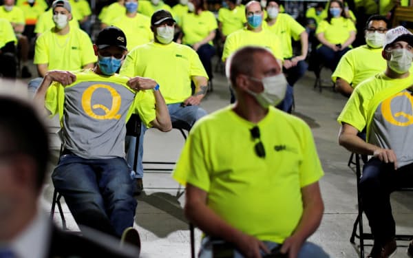 トランプ米大統領の演説会に出席し、黄色いユニホームの下に着込んだQアノンのTシャツを誇示する支持者。Qアノンはコロナ禍の中で勢いを増している=ロイター