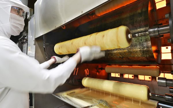専用の機械の中を回るバウムクーヘンを職人が形を整えながら焼き上げる=松浦弘昌撮影