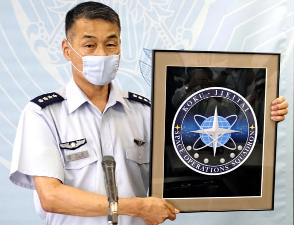航空自衛隊の宇宙作戦隊のシンボルマークを披露する丸茂吉成航空幕僚長(7月31日午後、防衛省)=共同