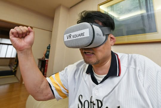 VRゴーグルを使い、自宅リビングで野球観戦を楽しむ近藤誠さん(東京都台東区)