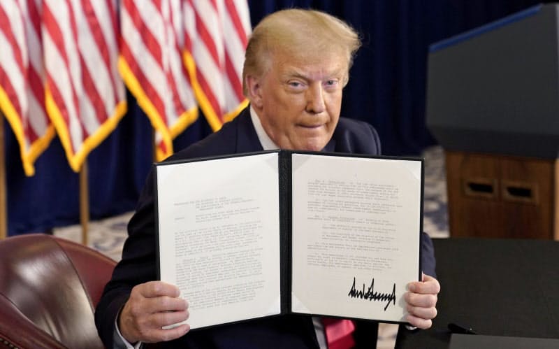8日、米ニュージャージー州での記者会見で、署名した大統領令を示すトランプ米大統領=ロイター 8日、米ニュージャージー州での記者会見で、署名した大統領令を示すトランプ米大統領=ロイター