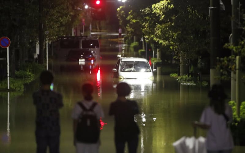 台風19号による大雨で冠水した住宅地の道路を見つめる人たち(2019年10月12日、東京都世田谷区)=共同 台風19号による大雨で冠水した住宅地の道路を見つめる人たち(2019年10月12日、東京都世田谷区)=共同