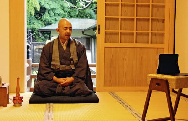 座禅の組み方について説明する、富春山桂林寺の織田宗泰副住職(7月27日、山梨県都留市)=共同
