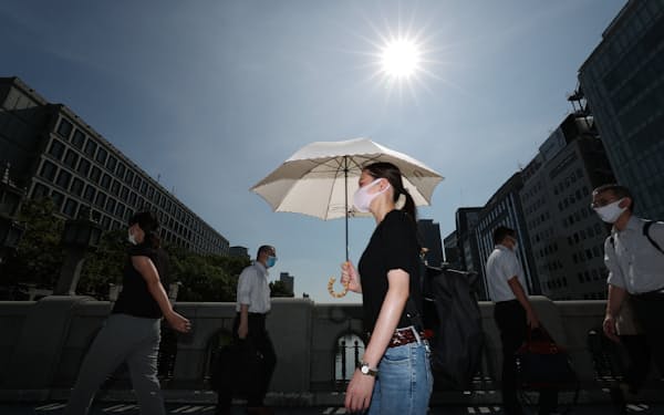 強い日差しの下、日傘をさして歩く人たち（19日午前、大阪市北区）