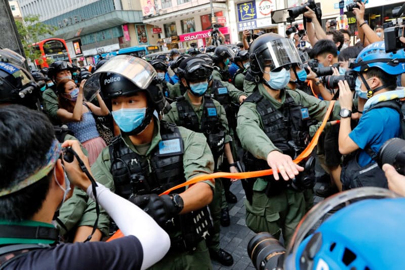 デモを取り締まるマスク姿の警察官ら(6日、香港)=ロイター デモを取り締まるマスク姿の警察官ら(6日、香港)=ロイター