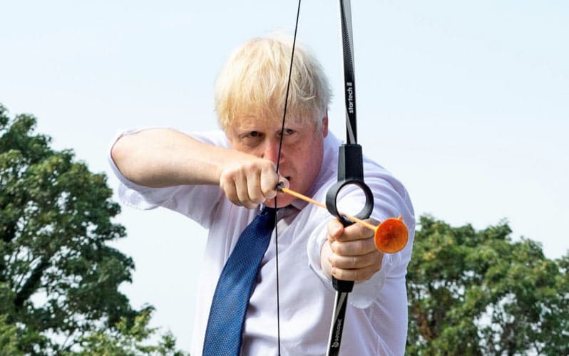 訪れたキャンプ場で矢をつがえてみせるジョンソン英首相(8月、ロンドン・アップミンスター)=ロイター 訪れたキャンプ場で矢をつがえてみせるジョンソン英首相(8月、ロンドン・アップミンスター)=ロイター