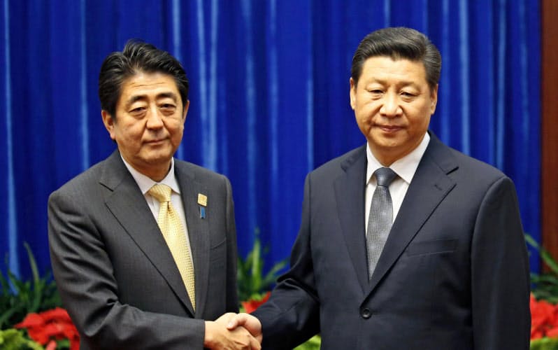 2014年11月、仏頂面をした中国の習近平国家主席(右)と握手する安倍首相(北京の人民大会堂)=共同 2014年11月、仏頂面をした中国の習近平国家主席(右)と握手する安倍首相(北京の人民大会堂)=共同
